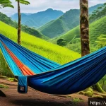Home 23 최고의 캠핑용 해먹 추천 - A lightweight camping hammock made of nylon fabric, hanging between two lush green trees in a Vietna...